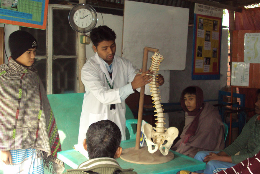 A man points to a model of a spine in a group of students