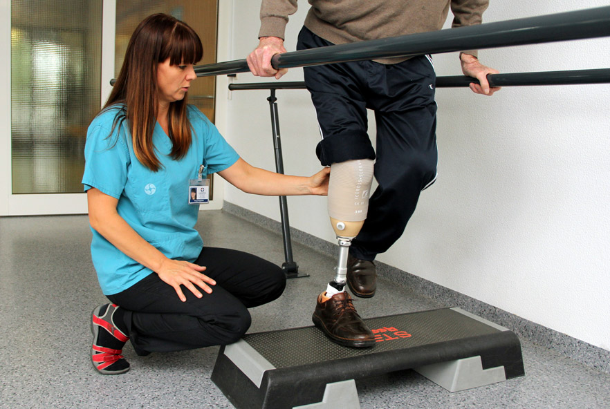 A physiotherapist makes adjustments to a patient's prosthetic leg