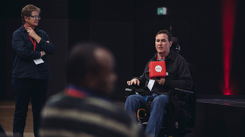 A man in a wheelchair talks to the audience